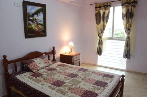 1 dormitorio con 1 cama con edredón y ventana en Apartamentos El Mirador en El Carmen