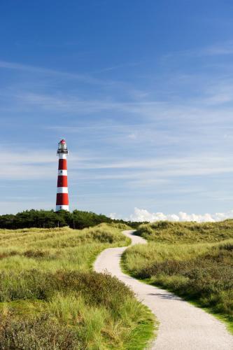 a red and white lighthouse in the middle of a field at 't STRANDHUYS en DE VUURTOREN, met eigen KEUKEN, ZONNIG TERRAS nabij DORP, DUINEN en STRAND, Incl verwarmd binnen ZWEMBAD in Hollum