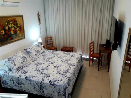 1 dormitorio con 1 cama, mesa y sillas en Suítes Cambucá en Ilhabela