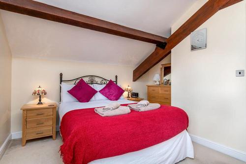 a bedroom with a red bed with two towels on it at Tregarnedd Cottage in Llangefni