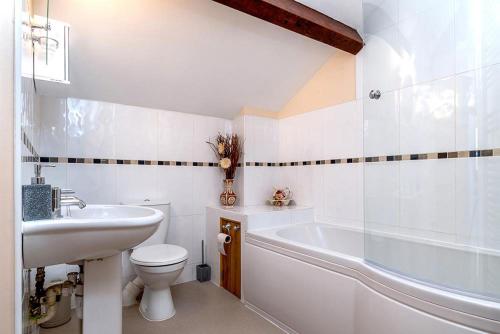 La salle de bains est pourvue d'un lavabo, d'une baignoire et de toilettes. dans l'établissement Tregarnedd Cottage, à Llangefni