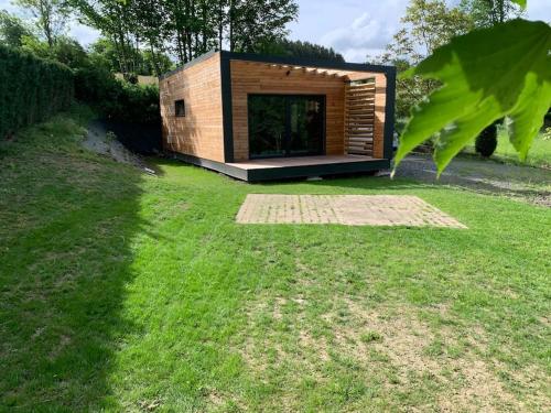 a small wooden building on a grassy field at Le cabanon in Houffalize