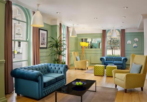 a living room with blue furniture and green walls at Citadines South Kensington London in London