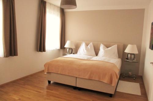 ein Schlafzimmer mit einem Bett mit weißen Kissen und einem Fenster in der Unterkunft Apartment Velden - Angelika Berginz in Velden am Wörthersee