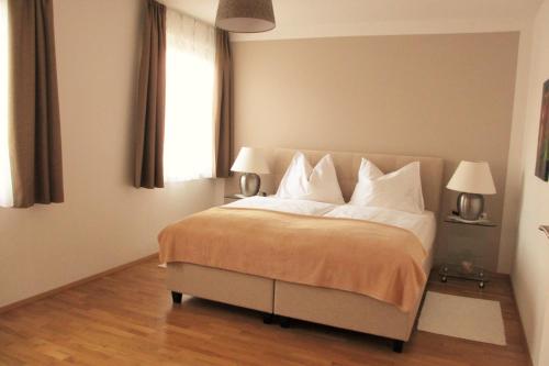 a bedroom with a bed with white pillows and a window at Apartment Velden - Angelika Berginz in Velden am Wörthersee