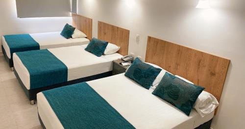 a room with three beds with blue and white at Hotel Ruittoque D Prada in Bucaramanga