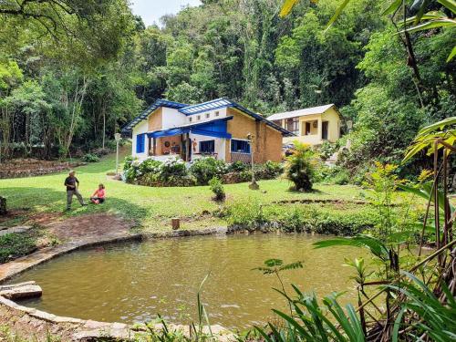 Ein Mann und ein Kind vor einem Haus neben einem Teich in der Unterkunft Sitio Anju in Atibaia