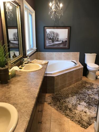 a bathroom with a tub and a sink and a toilet at Cozy Luxury on the Thames in Ontario! in London