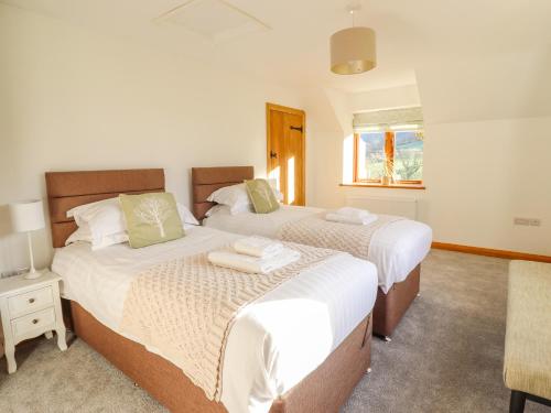a bedroom with two beds and a table and a window at Cwmwr in Pen-y-bont-fawr