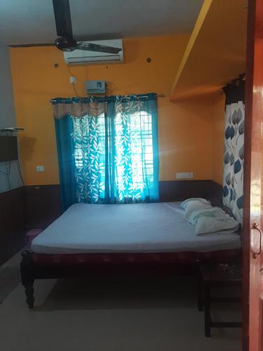 a bed in a room with a blue window at NAVENDU HOMESTAY in Alleppey