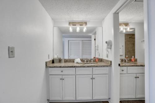 a white bathroom with a sink and a mirror at Sandcastle Villas 215-216 in Fernandina Beach