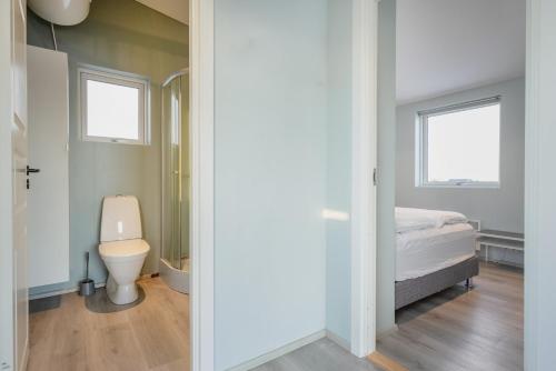 a bathroom with a toilet and a bed in a room at Sula Guesthouse in Selfoss