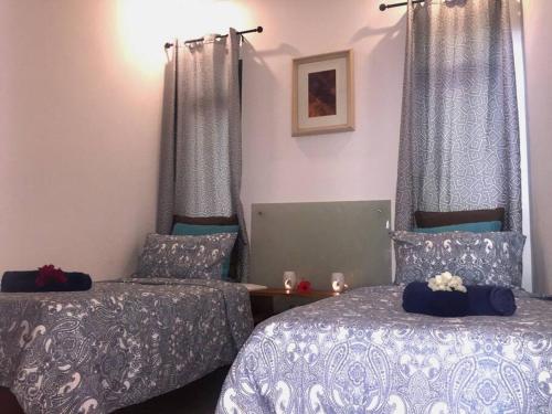 1 dormitorio con 2 camas, mesa y cortinas en les Villas Thorel -Hibiscus, en Rivière Noire