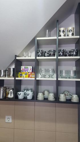 Una cocina con estantes llenos de cuencos y platos. en Apartman Adzic, en Zlatibor