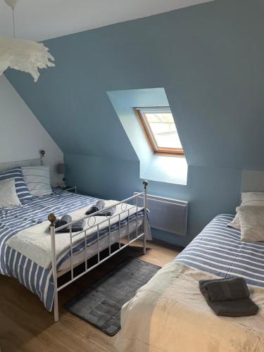 a blue bedroom with two beds and a skylight at Cocon douillet en bord de mer in Grandcamp-Maisy