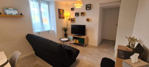 a living room with a couch and a tv at La Campagne à la ville dans pavillon avec jardin Clos et privatif in Héricourt