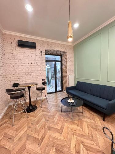 Charming Apartment near Marjanishvili Square في تبليسي: غرفة معيشة مع أريكة زرقاء وجدار من الطوب
