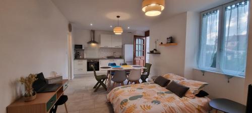 a bedroom with a bed and a kitchen with a table at La Campagne à la ville dans pavillon avec jardin Clos et privatif in Héricourt