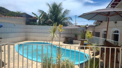 uma piscina com uma cerca e um guarda-sol em Hotel Lazaro Ubatuba Ltda em Ubatuba