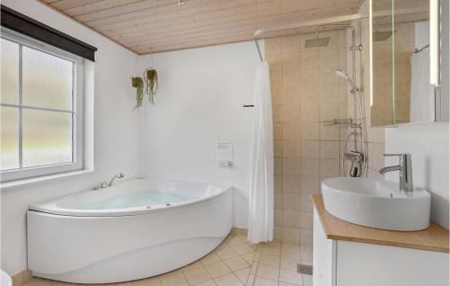 a bathroom with a large white tub and a sink at Stunning Home In Grsten With Sauna in Gråsten