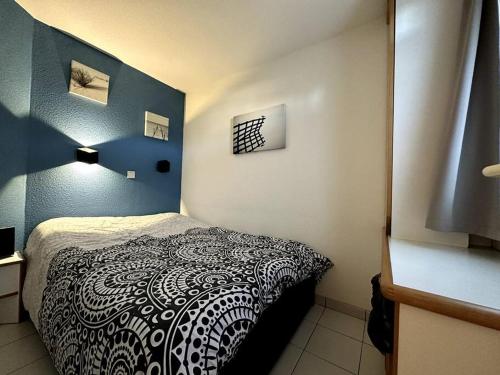 ein Schlafzimmer mit einem Bett mit einer schwarzen und weißen Decke in der Unterkunft Appartement vue Port Bourgenay, emplacement idéal in Talmont