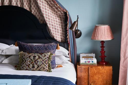 a bed with a black headboard and a table with a lamp at Beaverbrook Town House in London