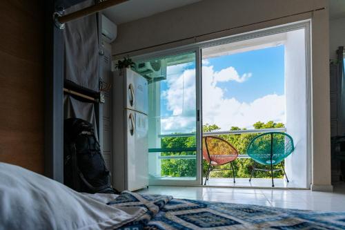 a bedroom with a bed and a large window at Hostal Cuca Macuca in Puerto Morelos