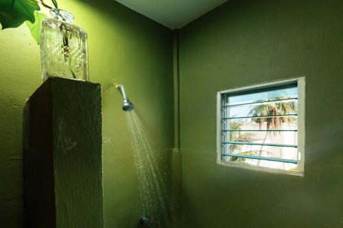 baño verde con ducha y ventana en Hostal Cuca Macuca, en Puerto Morelos