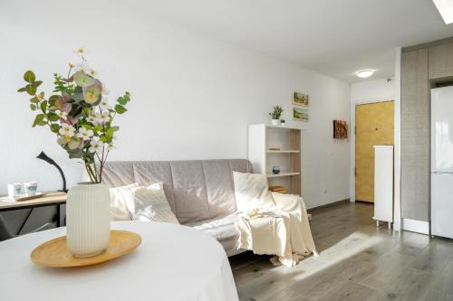 una sala de estar con sofá y un jarrón de flores sobre una mesa en Alea Rentals - Adriático en La Pineda
