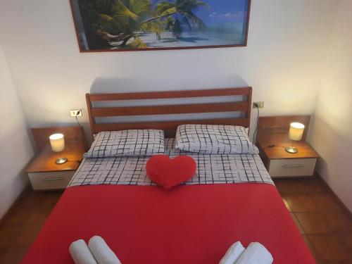 a bed with a red heart on top of it at Appartamenti Leonardo Airport in Azzano San Paolo
