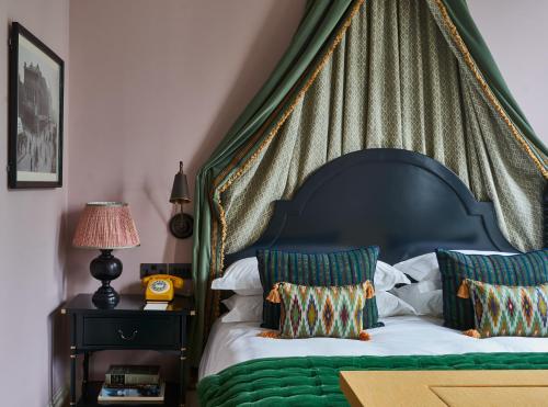 a bedroom with a green canopy bed with two pillows at Beaverbrook Town House in London