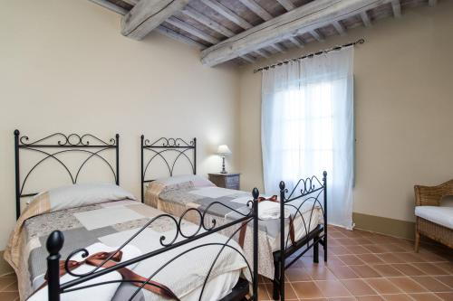 2 Einzelbetten in einem Zimmer mit Fenster in der Unterkunft Apartment Olivo in Trequanda