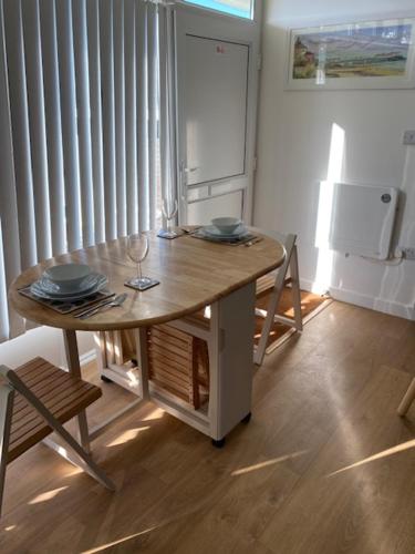 a table and chairs in a kitchen with a refrigerator at The View. Stylish modern Chalet in great location. in Cromer