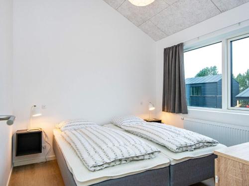 a white bedroom with a bed and a window at Holiday home Rømø CXXV in Sønderby