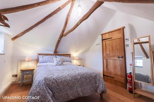 a bedroom with a bed and a wooden floor at UpAlong Cottage - HiddenDevon in Winkleigh