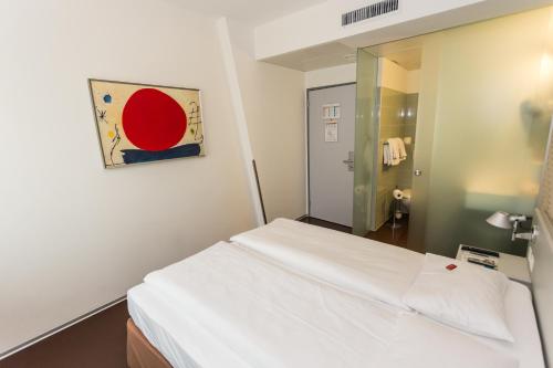 1 dormitorio con cama blanca y espejo en Sorell Hotel Ador en Berna