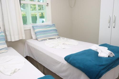 2 camas individuales en una habitación con ventana en PRAIA DE TAPERAPUAN - FLAT EM CONDOMINIO A 300 METROS DA PRAIA., en Porto Seguro