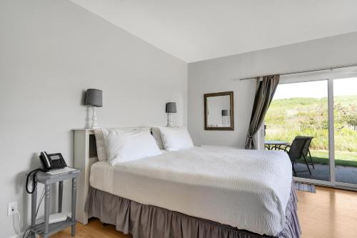 a white bedroom with a bed and a window at Windward Shores in Amagansett