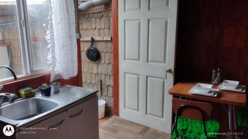cocina con fregadero, ventana y puerta en Cucao Chiloe, en Chonchi