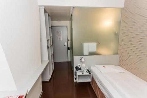 a hospital room with a bed and a mirror at Sorell Hotel Ador in Bern