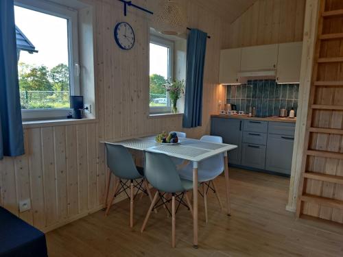 a kitchen with a table and chairs and a clock on the wall at Domek z balią in Chmielno