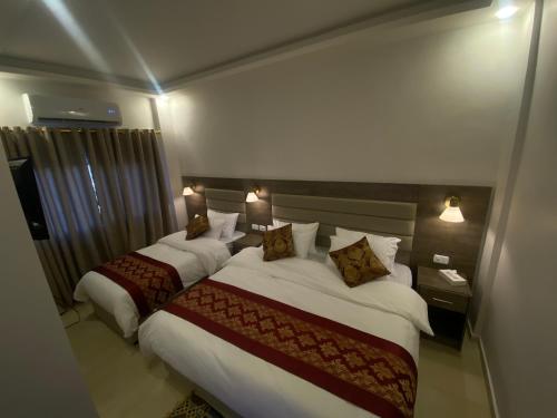 a hotel room with two beds and two lamps at Petra Oleander Hotel in Wadi Musa