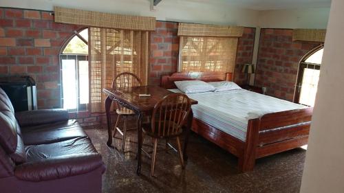 a bedroom with a bed and a desk and a table at Hotel Paramuru in Paramaribo