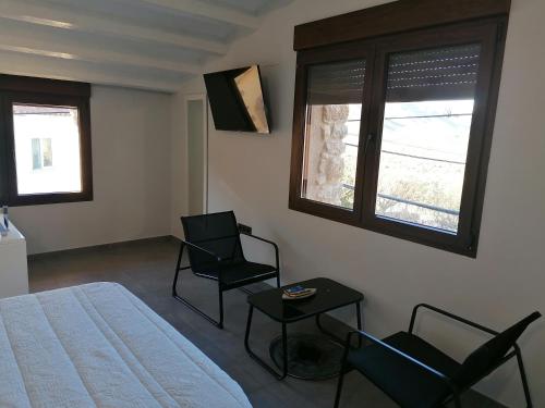 a bedroom with two chairs and a bed and two windows at CASA RURAL MENSIN in Villar de Canes