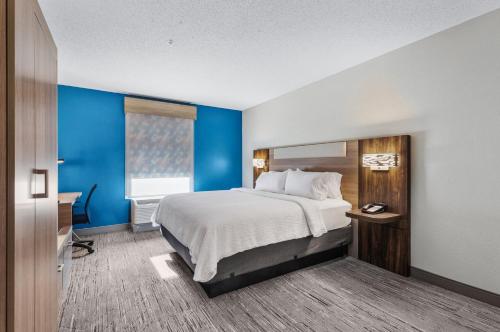 een hotelkamer met een bed en een blauwe muur bij Holiday Inn Express New Albany, an IHG Hotel in New Albany