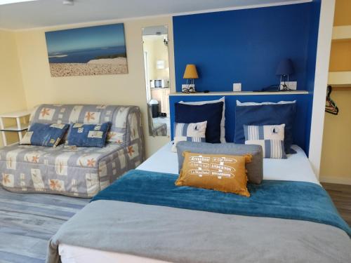 um quarto com paredes azuis, uma cama e um sofá em cottage la dune avec piscine les cigales du bassin à Gujan-Mestras em Gujan-Mestras