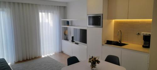 a kitchen with a table with chairs and a tv at Light Brown Central Apartment in Aveiro