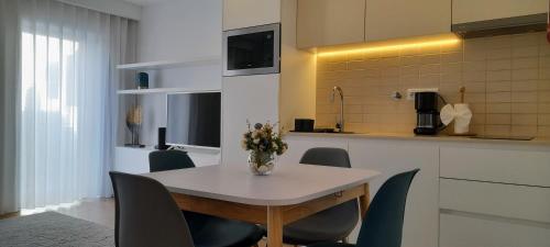 een tafel met stoelen en een vaas met bloemen erop bij Light Brown Central Apartment in Aveiro