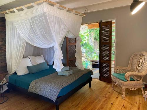 a bedroom with a bed with a canopy and a chair at Villa Acoma Lodge in Grand-Bourg