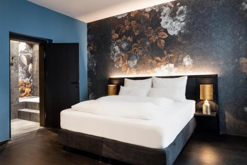 a bedroom with a large white bed with a painting on the wall at Aiola Living Graz in Graz